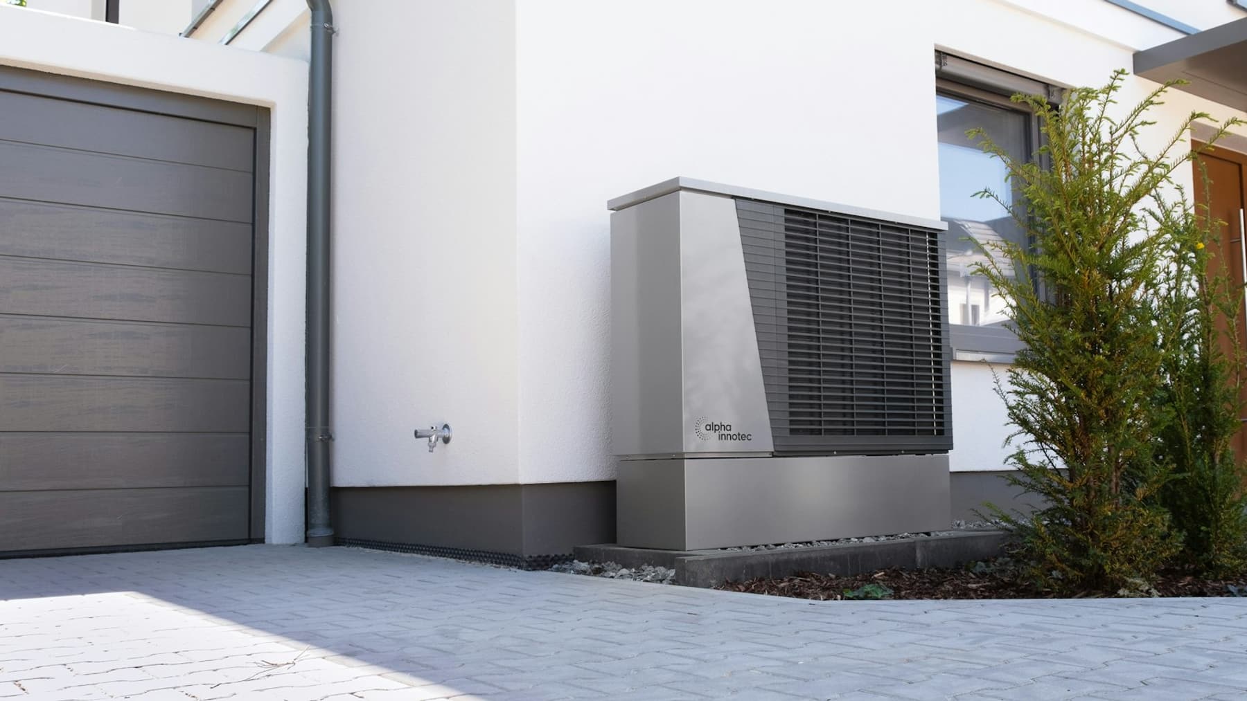 Heat pump unit installed outside a bright modern home on a sunny day