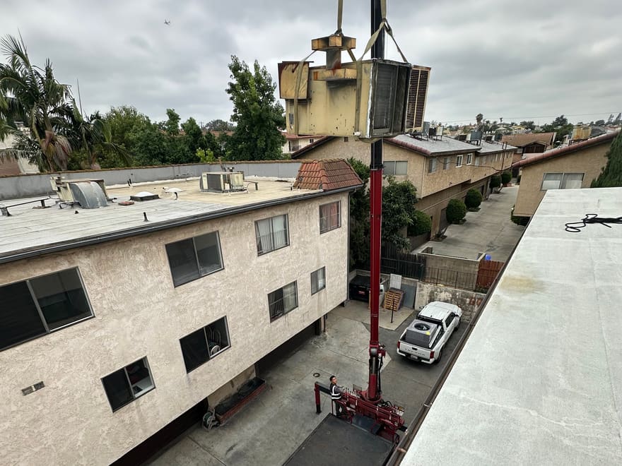 WJC crane truck lifting an old rooftop unit off a Los Angeles apartment building